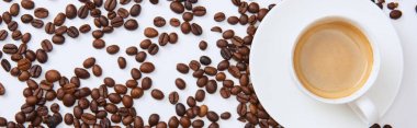 top view of coffee in cup on saucer near scattered roasted beans, panoramic shot clipart