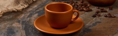 panoramic shot of brown cup on saucer on marble table clipart
