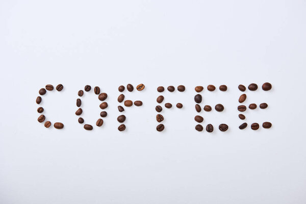 top view of coffee lettering made of coffee beans on white background