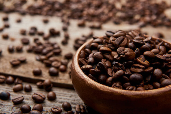 close up view of roasted coffee beans in bowl on wooden board
