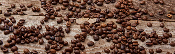 panoramic shot of wooden rustic table with scattered roasted coffee beans