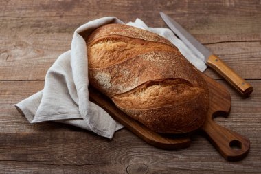 ahşap masada doğrama tahta üzerinde bıçak yakın peçete taze pişmiş ekmek somun