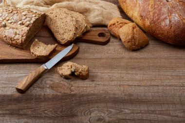 taze kesim ve tüm ekmek somun ve çörekler, bıçak ve ahşap masa üzerinde bez yakın Doğrama tahtası