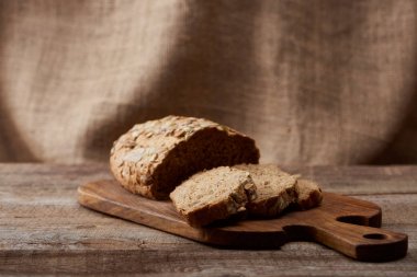 arka planda korbez ile ahşap doğrama tahtasında lezzetli dilimlenmiş kahverengi ekmek