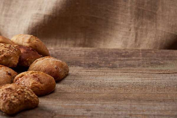 вкусные хлебы на деревянном столе со вретищем на заднем плане
