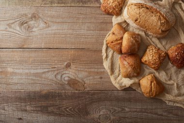 ahşap masa üzerinde bez üzerinde taze pişmiş ekmek ve çörekler üst görünümü