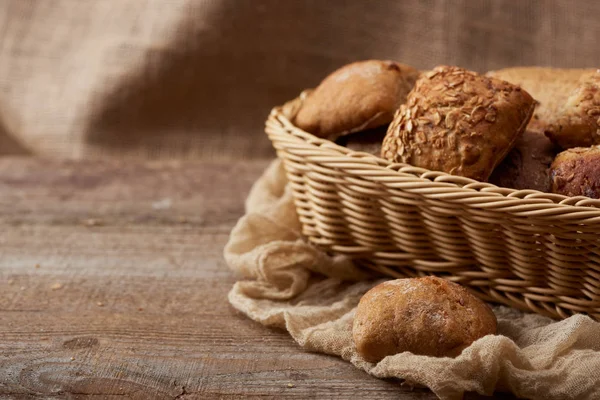 delicious fresh buns in wicker box on wooden rustic table with cloth with copy space