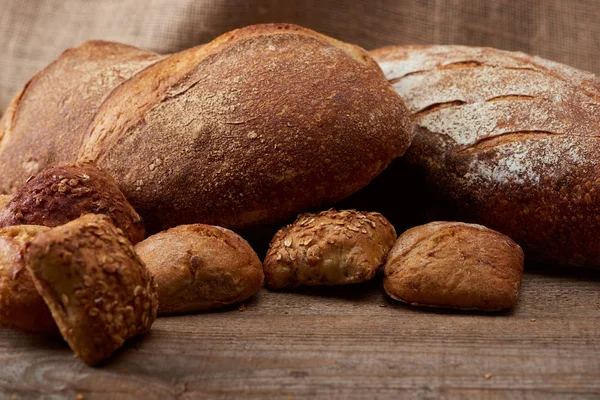 新鲜烤面包和面包的选择性焦点在木桌上 背景是麻布 — 图库照片