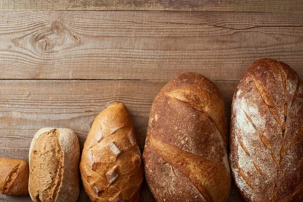 木製の素朴なテーブルの上にパンの新鮮な自家製パンのトップビュー — ストック写真
