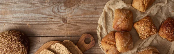 在木制质朴的桌子上新鲜面包和包子的顶视图 全景拍摄 — 图库照片