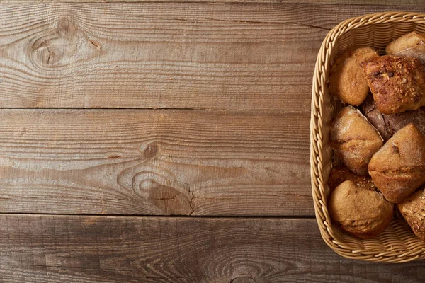 木製のテーブルの上に焼きたてのパンとウィッカーバスケットのトップビュー — ストック写真