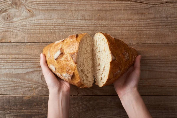 Cropped View Woman Holding Fresh Baked Bread Halves Wooden Table — Stock Photo, Image