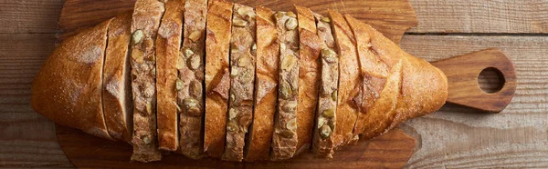 木製のまな板にローフの種子と白と茶色のパンのスライスのトップビュー パノラマショット — ストック写真