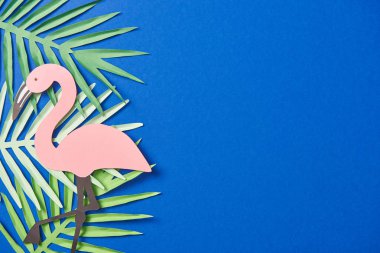 kopya alanı ile mavi arka plan üzerinde yeşil kağıt kesme egzotik yaprakları ve flamingo üst görünümü