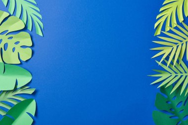 kopya alanı ile mavi arka plan üzerinde yeşil kağıt kesilmiş egzotik yaprakları üst görünümü