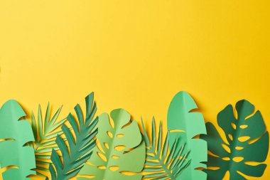 top view of paper cut green palm leaves on yellow background with copy space clipart