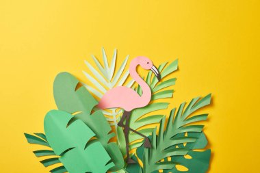 kopya alanı ile sarı arka plan üzerinde kağıt kesilmiş yeşil palmiye yaprakları ve pembe flamingo üst görünümü