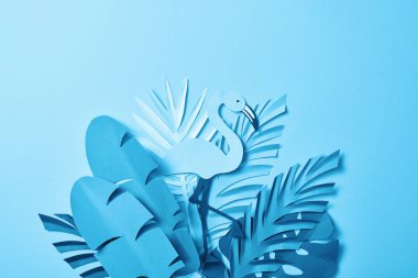 kopya alanı ile mavi arka plan üzerinde palmiye yaprakları üzerinde mavi minimalist kağıt kesme flamingo üst görünümü