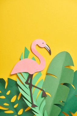 kağıt kesme yeşil palmiye yaprakları ve sarı arka plan üzerinde sevimli flamingo üst görünümü 