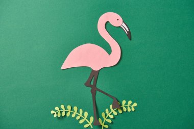 yeşil arka plan üzerinde kağıt kesilmiş yaprakları ve pembe flamingo üst görünümü