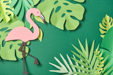 kopya alanı ile yeşil arka plan üzerinde egzotik kağıt kesilmiş palmiye yaprakları ve pembe flamingo üst görünümü