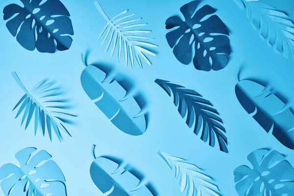 seamless pattern of blue minimalistic paper cut palm leaves on blue background
