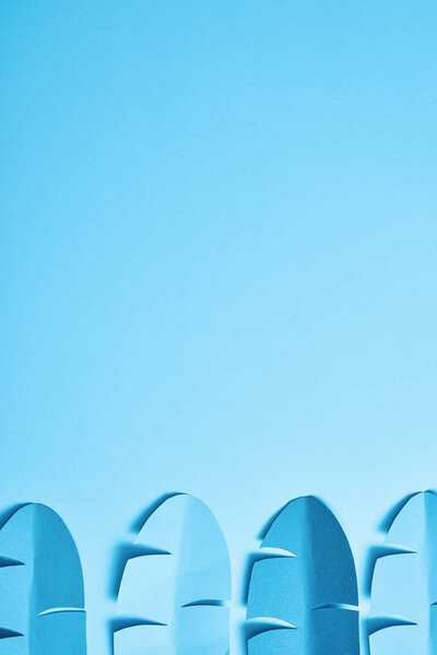 top view of blue minimalistic paper cut palm leaves on blue background with copy space