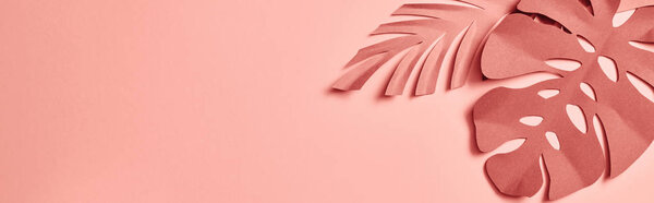 panoramic shot of paper cut decorative palm leaves on pink background