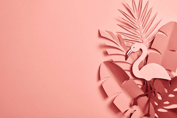 top view of paper cut palm leaves and decorative flamingo on pink background with copy space