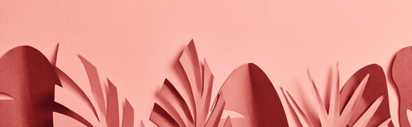 panoramic shot of paper cut decorative palm leaves on pink background