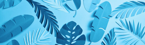 panoramic shot of blue minimalistic paper cut palm leaves on blue background with copy space, seamless pattern