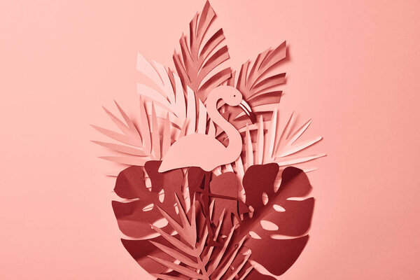 top view of flamingo and paper cut palm leaves on pink background