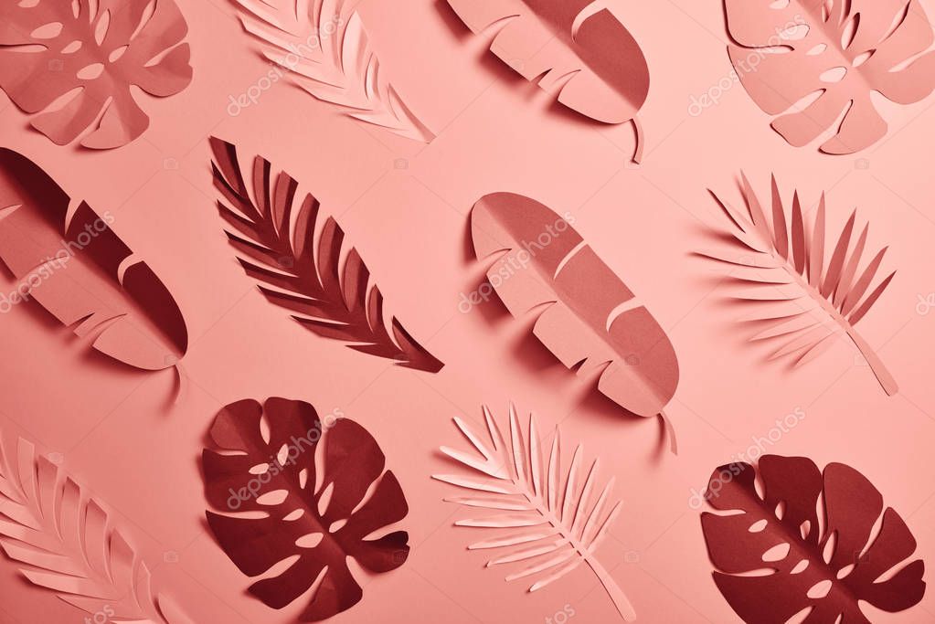 Top view of paper cut palm leaves on pink background, seamless pattern