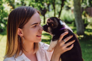 mutlu sarışın kız yeşil bahçede sevimli köpek yavrusu bakıyor