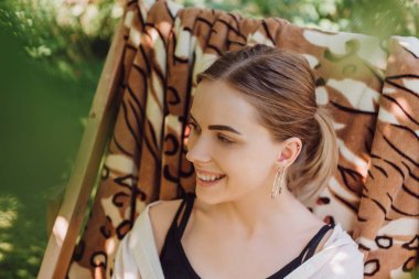 yeşil yaprakları ve bahçede şezlongoturan güzel mutlu sarışın kız seçici odak