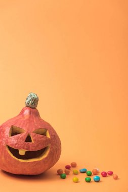 turuncu arka planda şekerler ile ürkütücü Halloween kabak