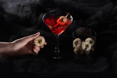 siyah bulutlar kırmızı Halloween kokteyl yakınında dekorasyon tutan kadın kırpılmış görünümü