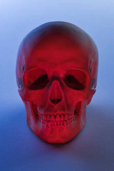 spooky human skull in red lighting on blue background, Halloween decoration