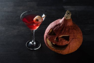 Halloween pumpkin and red cocktail on black background clipart