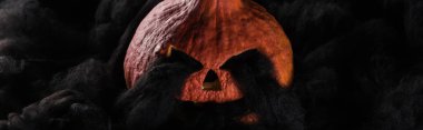 panoramic shot of spooky carved Halloween pumpkin with black clouds clipart