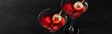 panoramic shot of red decorated Halloween cocktails on black background clipart