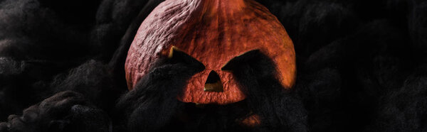 panoramic shot of spooky carved Halloween pumpkin with black clouds