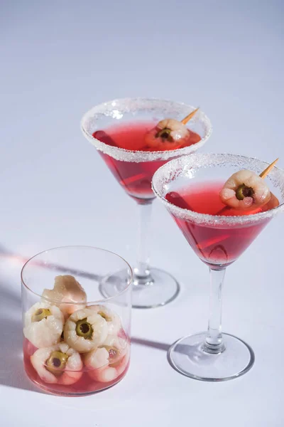 red sweet Halloween cocktails with decoration in glasses on white surface