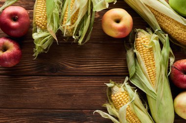 kopya alanı ile kahverengi ahşap yüzeyüzerinde taze elma ve tatlı mısır üst görünümü