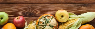 panoramic shot of fresh apples, pumpkins and sweet corn on wooden surface  clipart