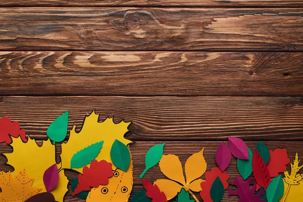 Kahverengi Ahşap Yüzeyüzerinde Renkli Kağıt Yaprakları Üst Görünümü — Stok fotoğraf