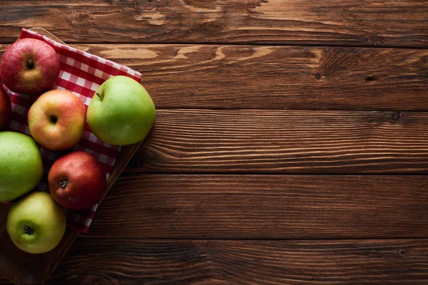 コピースペース付きの木製の表面に新鮮なリンゴとチェッカーテーブルクロスのトップビュー — ストック写真