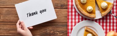 ahşap rustik masada kabak pasta yakınında teşekkür kartı tutan kadın kırpılmış görünümü