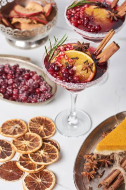 selective focus of christmas cocktails with orange, pomegranate and cinnamon, pie on tray 