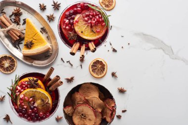 Portakal, nar, tarçın, tepside turta ve kuru elmayla noel kokteyllerinin üst görüntüsü. 